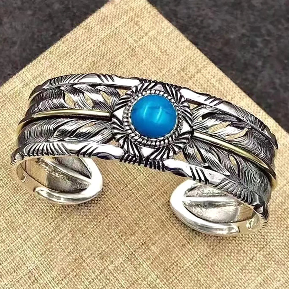 Close-up of the carved silver feathers and round turquoise stone on the two-tone cuff