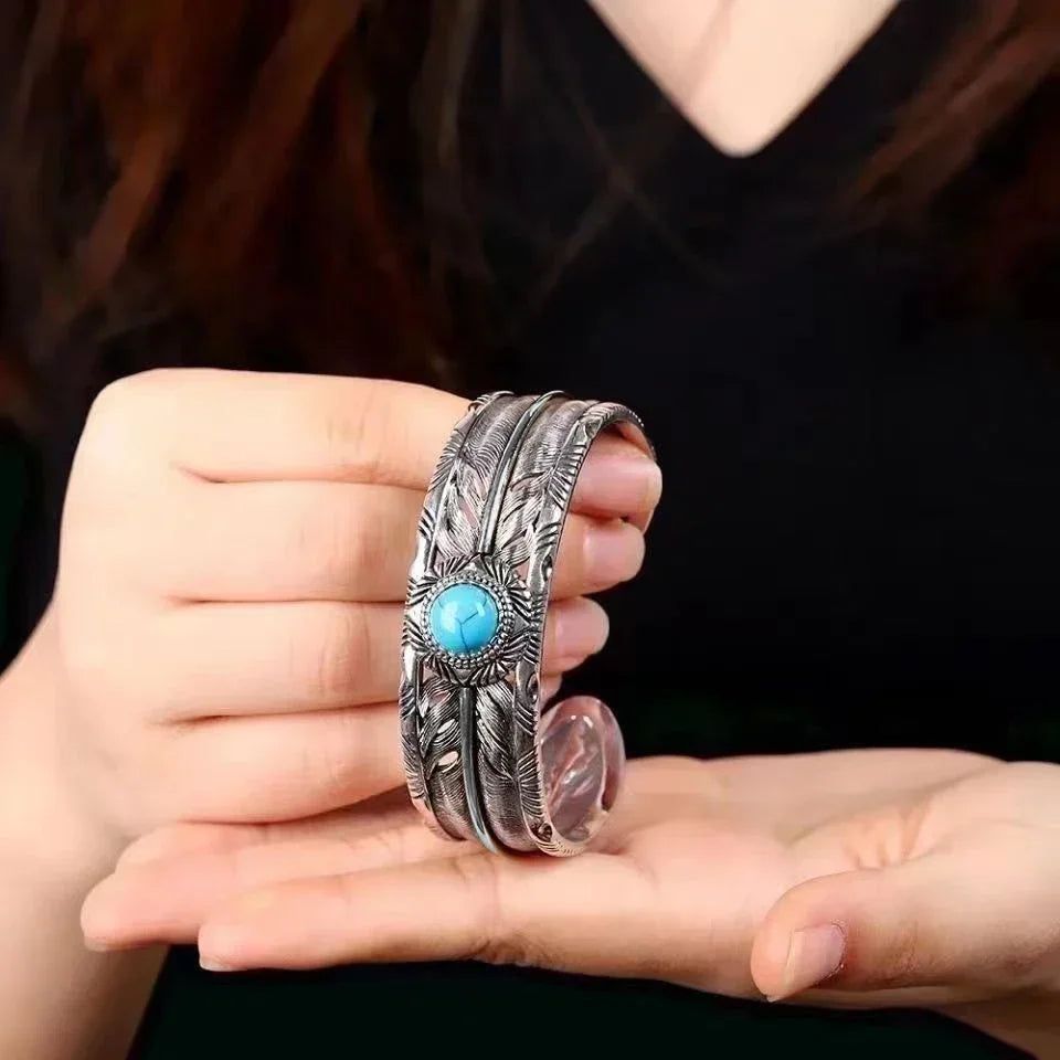 Turquoise feather silver open cuff held in hand to show its size