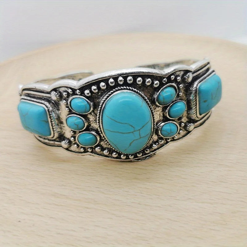 Front view of the wide silver cuff with a turquoise oval ringed by smaller stones